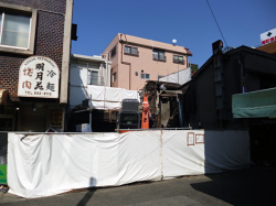 防音シートで囲われ、パワーショベルで解体されるおもちゃの店すぎやま。建物に看板が残る焼肉屋「名月苑」も2013年5月で閉店し、廃業しました。この焼肉屋はたくさんのファンを持つ地元の名店でした。オーナーがまた小さくても焼肉屋をはじめてくれるのを地元住民は心待ちしているようです。